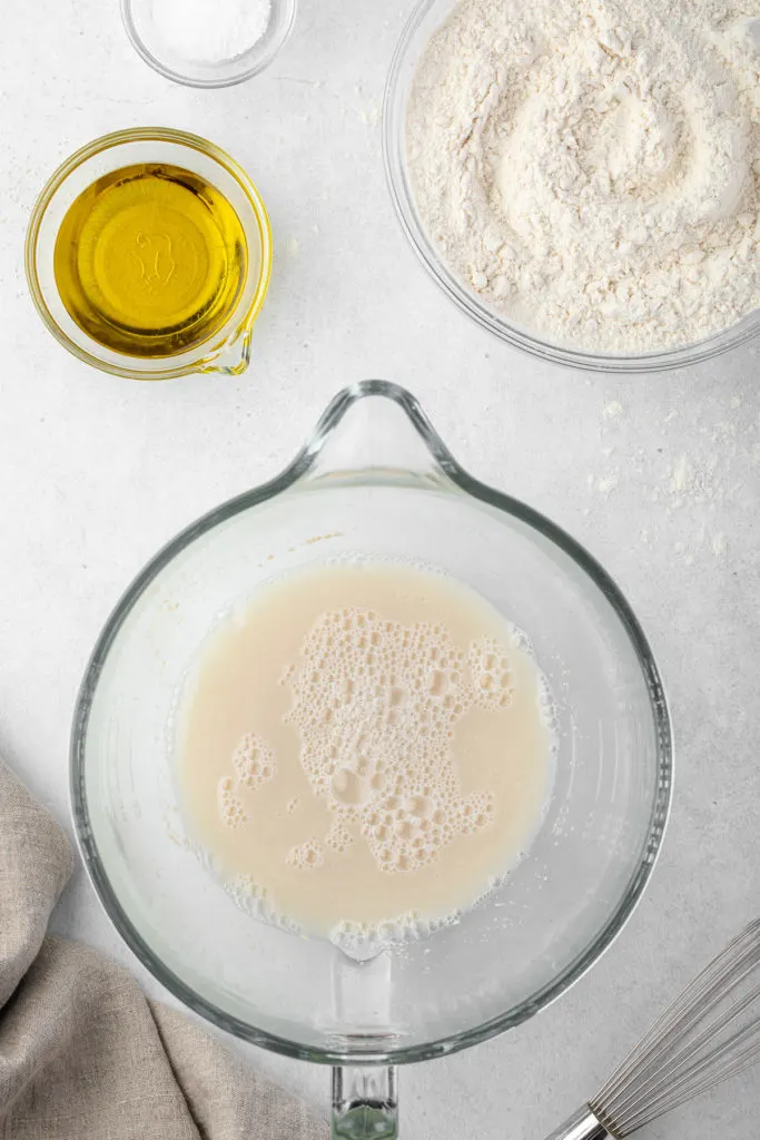 Yeast, water and sugar in a glass bowl.