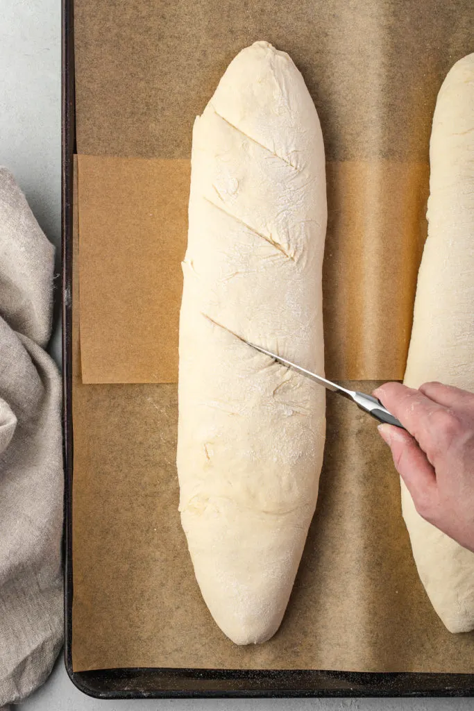 Slashes being cut in the top of bread.