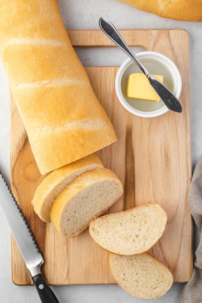 Top down view of a loaf of sliced bread with butter.