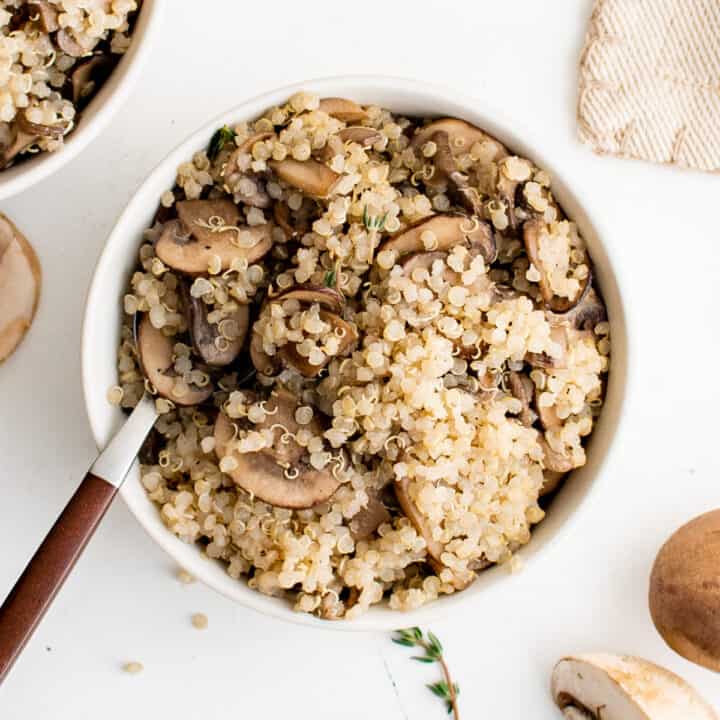 Close up view of a spoon in a bowl of mushroom quinoa.