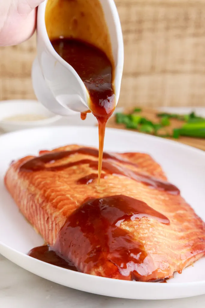 Teriyaki glaze being poured over salmon.