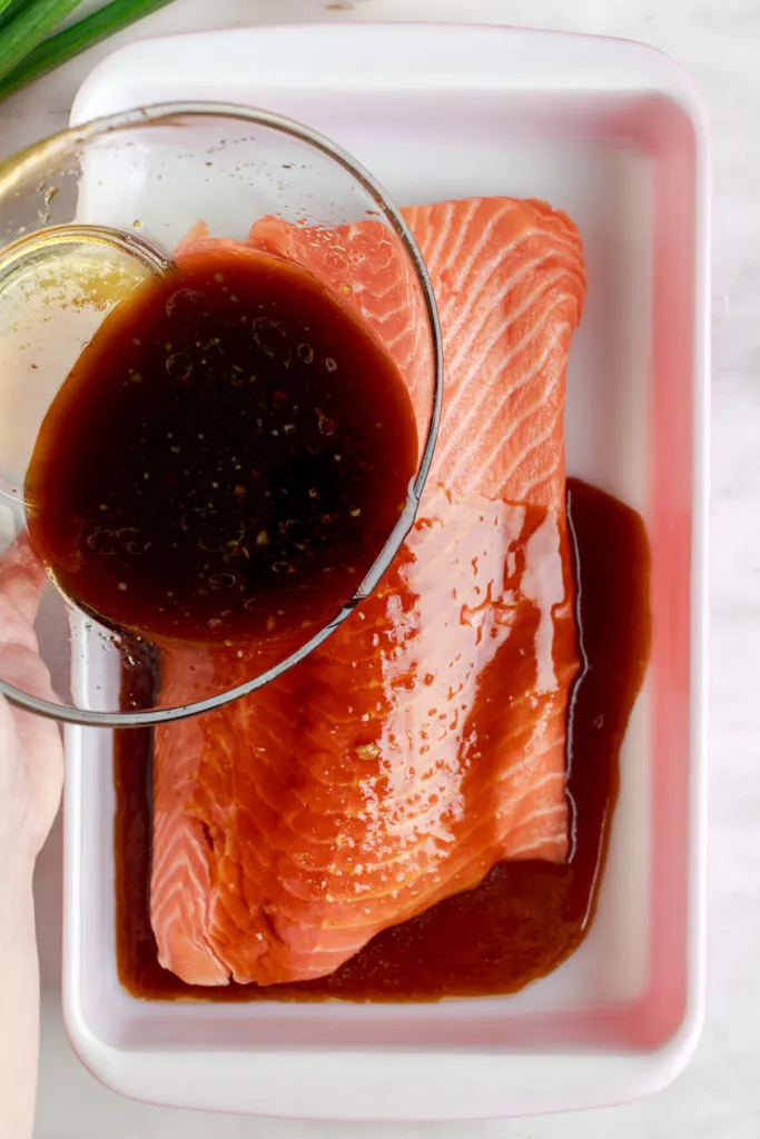 Teriyaki glaze being poured over salmon.