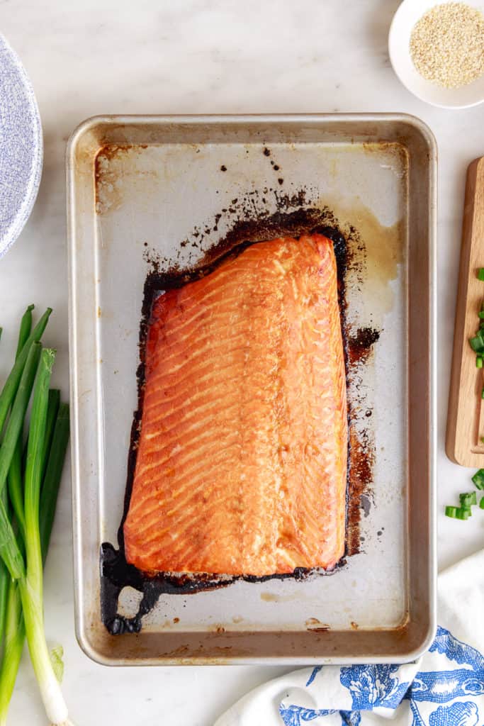 Top down view of a baked salmon fillet on a baking dish.