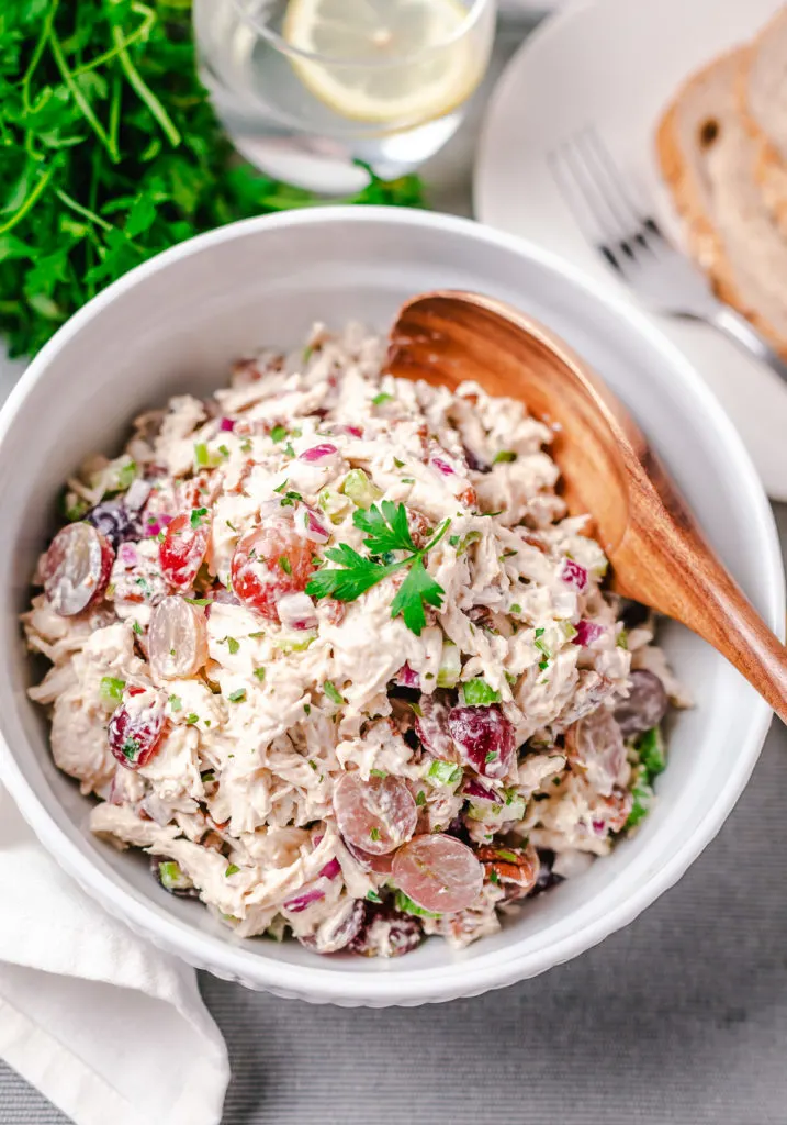 Grapes with chicken salad in a mixing bowl.