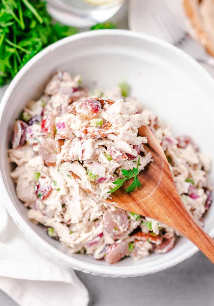 Mixed chicken salad on a wooden spoon.