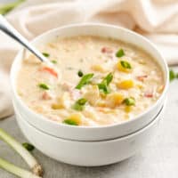 Spoon in a white bowl of crockpot ham and potato soup.