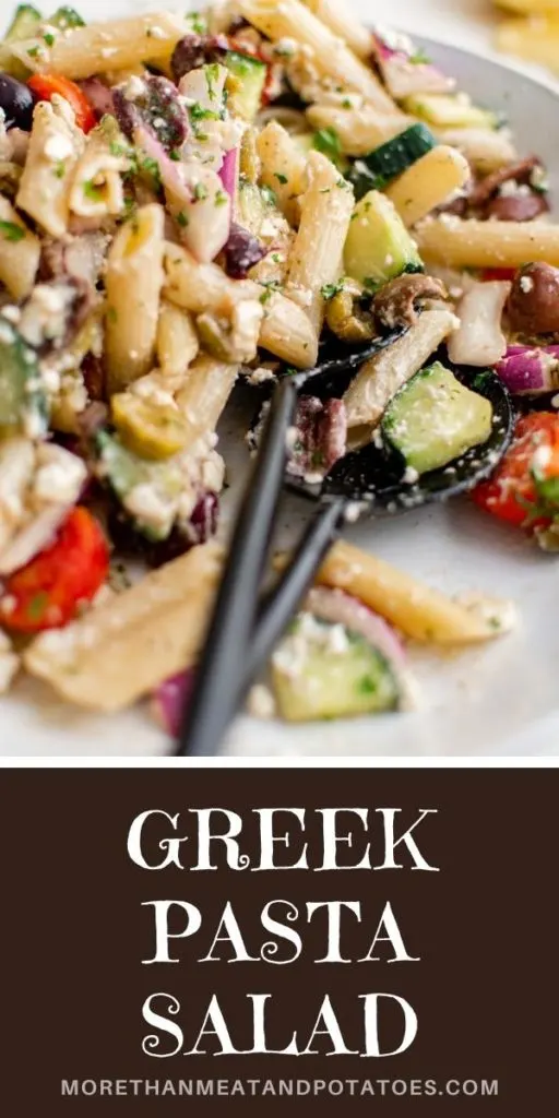 Side view of greek pasta salad with tongs in a serving dish.