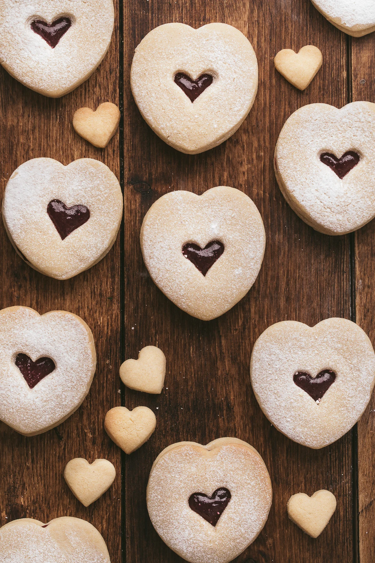 Several jam filled cookies on wood.