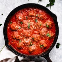 Top down view of baked meatballs in sauce.