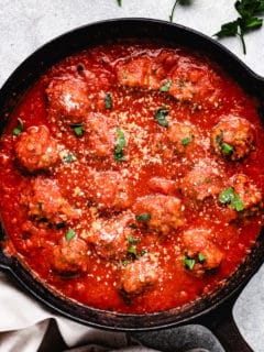 Top down view of baked meatballs in sauce.