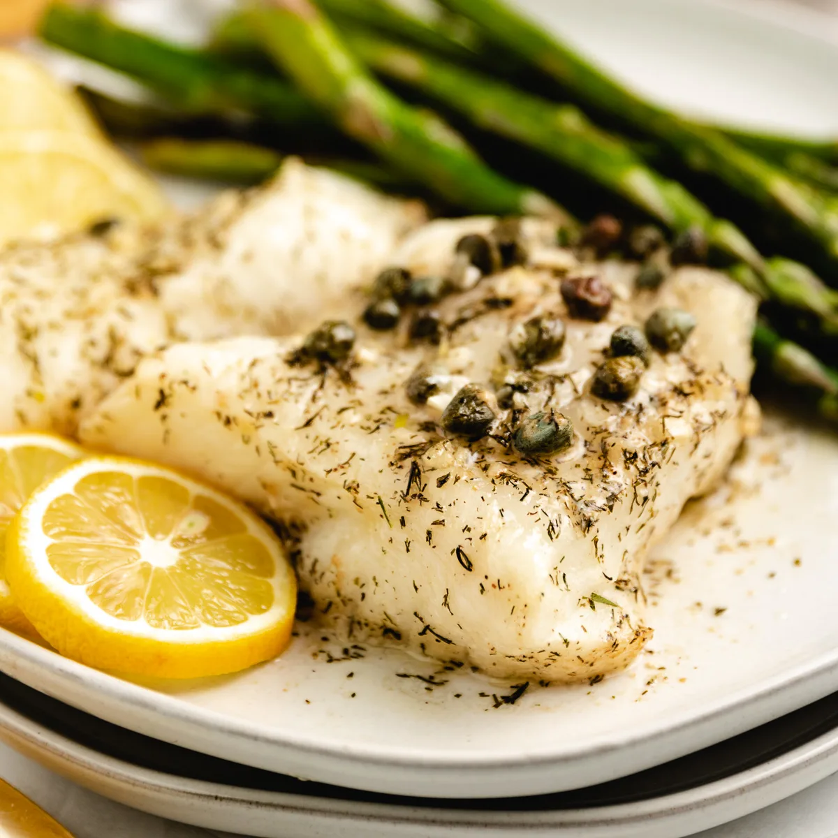 Sea bass on a white plate with lemon.