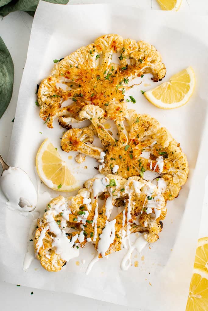 Cauliflower steaks with sauce and lemon.