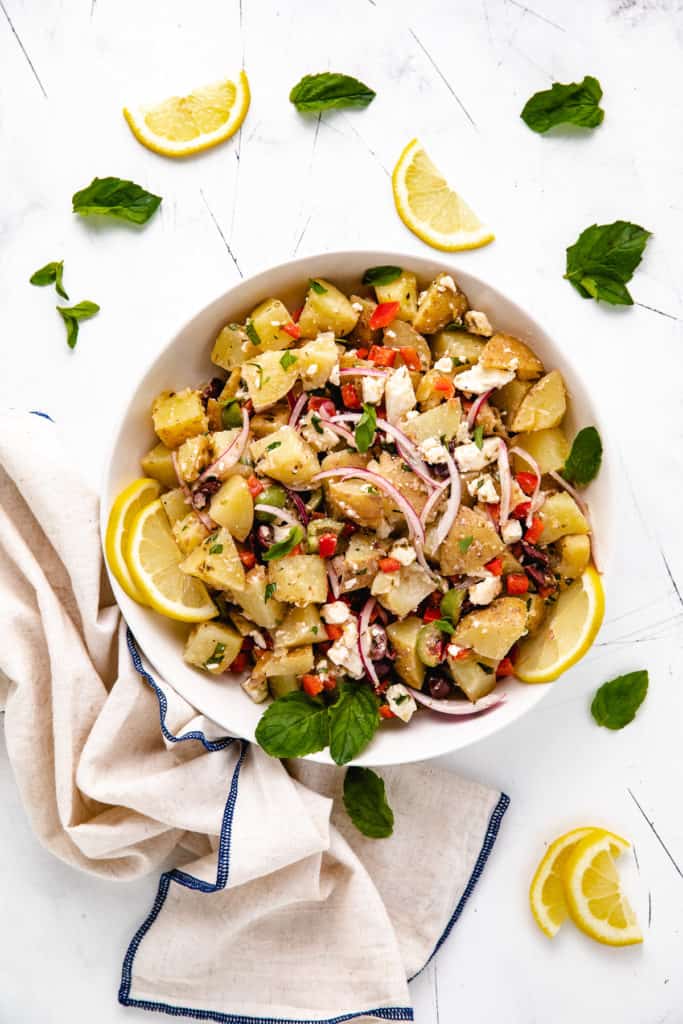 Greek potato salad with lemon slices in a bowl.