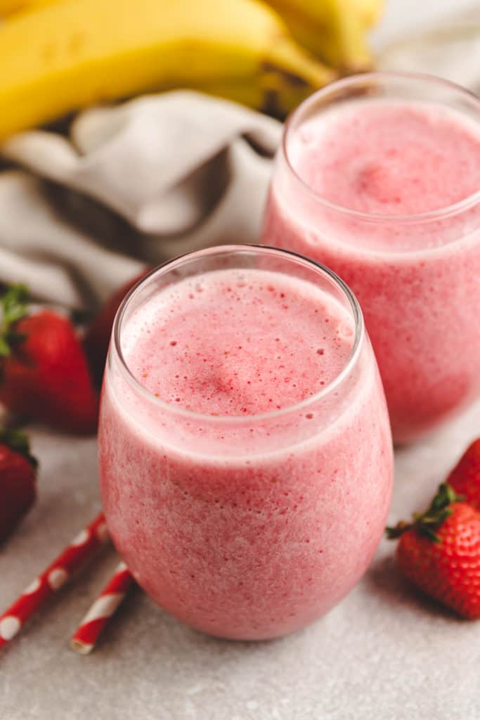 Two glasses filled with strawberry smoothies.