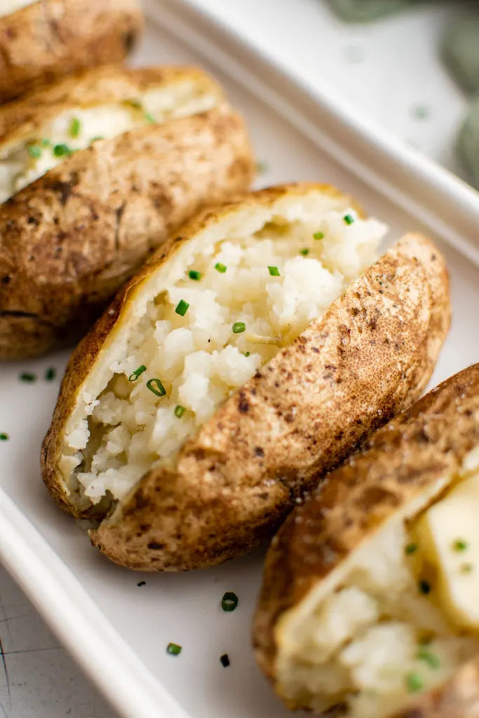 Side view of baked potatoes on a pan.