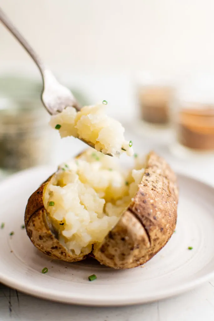 Bite of baked potato on a fork.