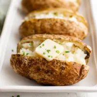 Baked potatoes on a white platter.