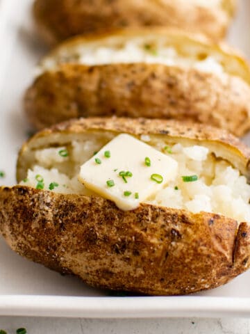 Baked potatoes on a white platter.