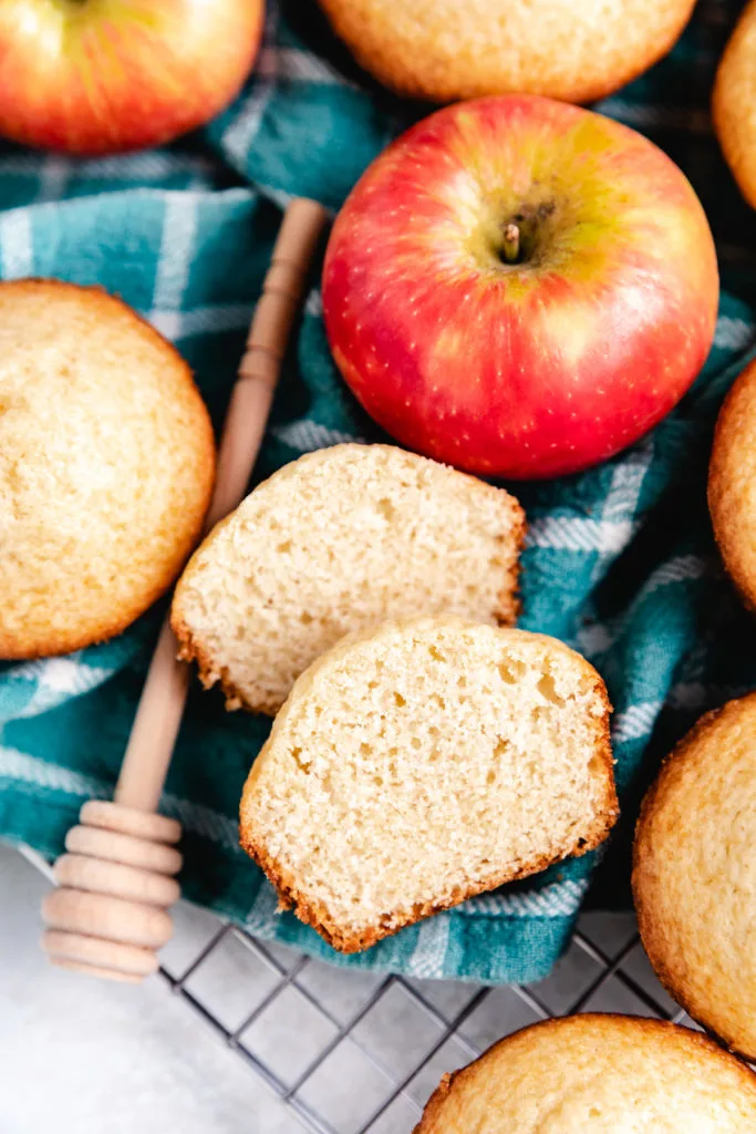 Muffin cut in half next to an apple.