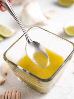 Spoon dipping into garlic lime dressing.