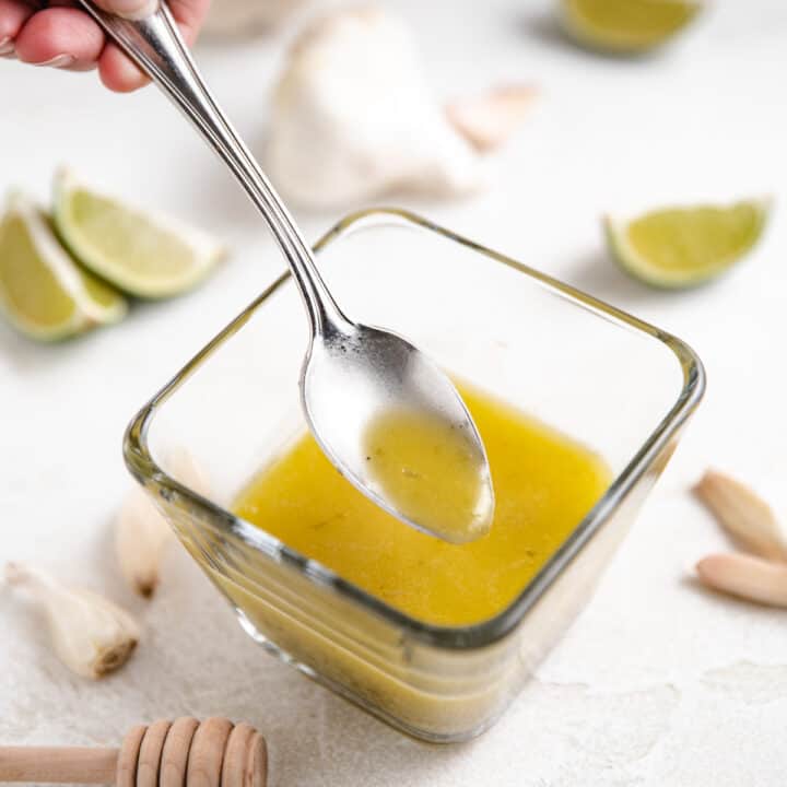 Spoon dipping into garlic lime dressing.