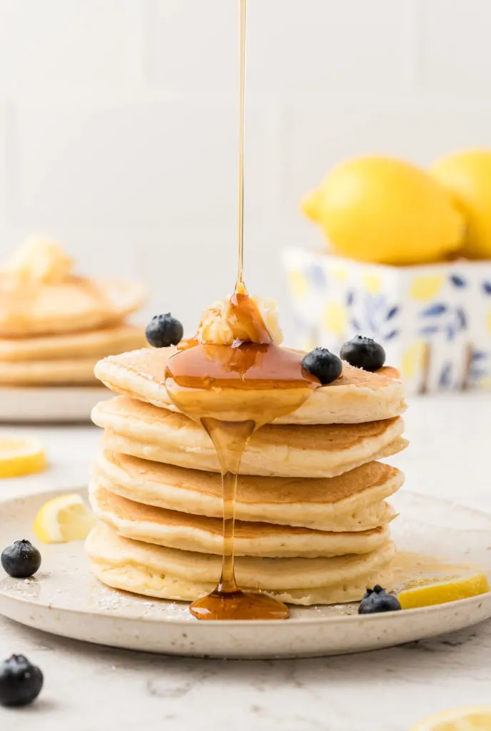 Syrup being poured over lemon ricotta pancakes.