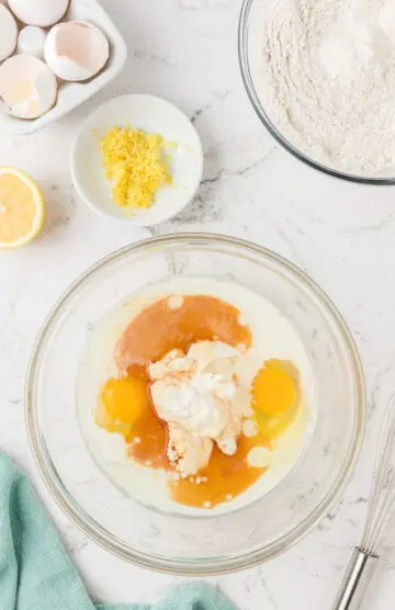 Eggs, milk, ricotta cheese, sugar, oil, and vanilla in a bowl.