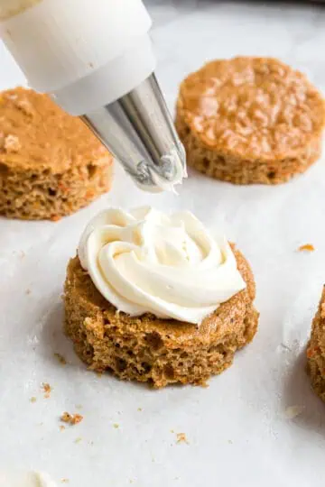 Cream cheese being added to a layer of cake.