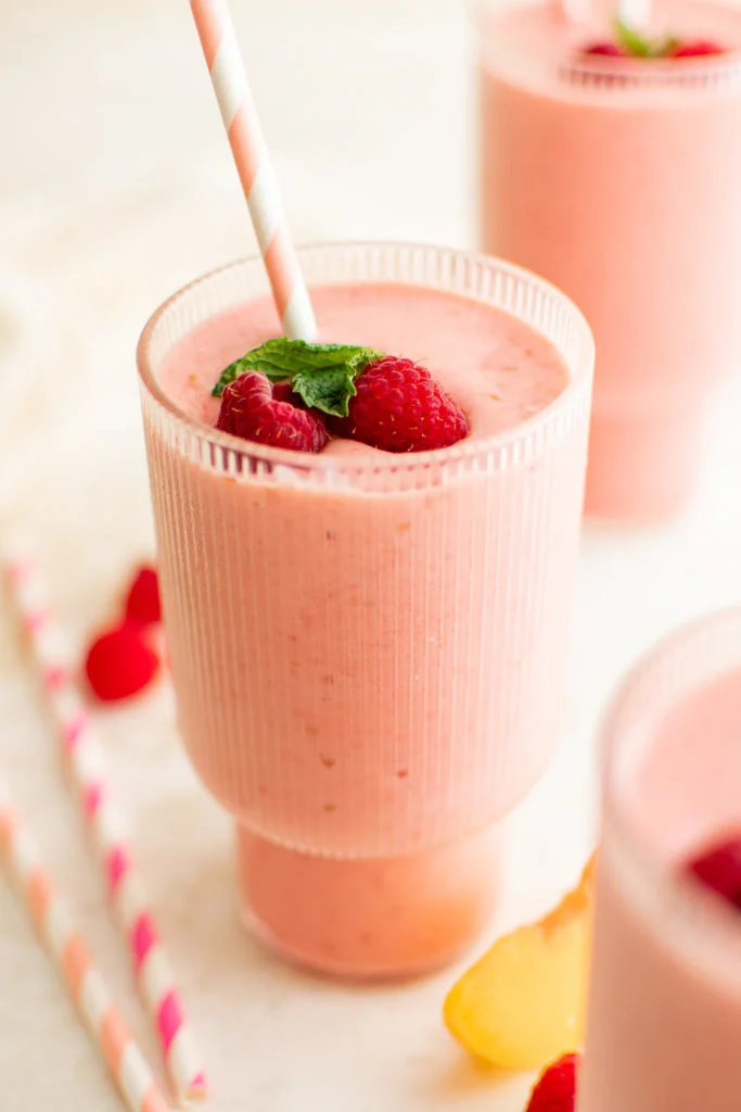 Tall glass containing a peach raspberry smoothie.