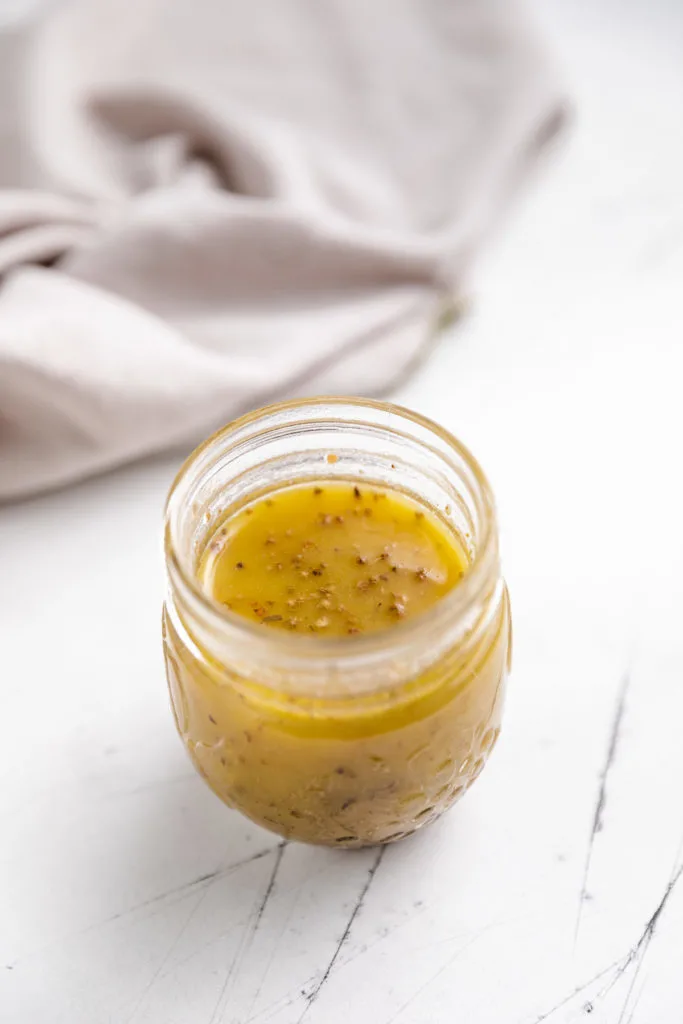 Mason jar filled with vinaigrette dressing.