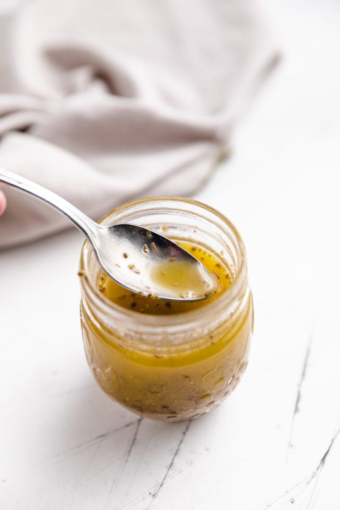 Spoon dipping into salad dressing.