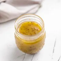 Small jar filled with vinaigrette dressing.