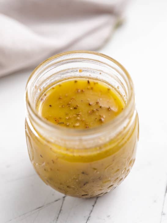 Small jar filled with vinaigrette dressing.