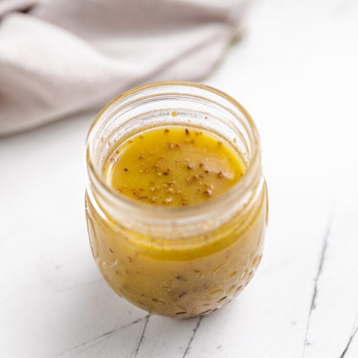 Small jar filled with vinaigrette dressing.