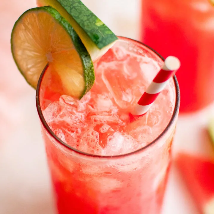 Tall glass of watermelon drink with a straw.