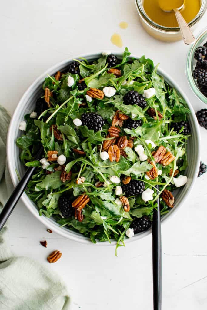Top down view of a salad with pecans, blackberries and cheese.