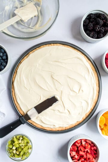 Cream cheese frosting being spread over a crust.