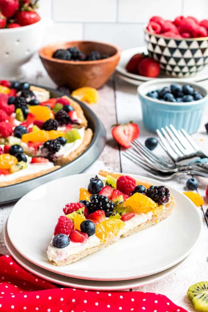 Slice of pizza topped with fruit on a plate.