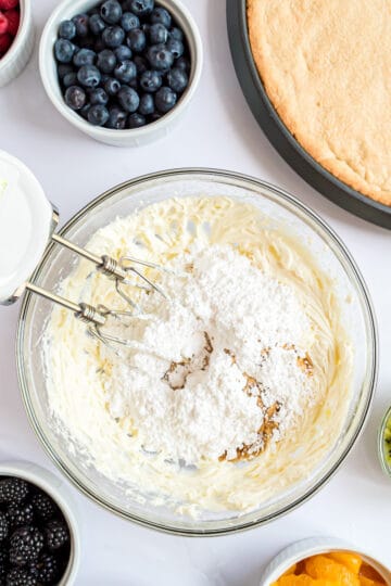 Powdered sugar added to a bowl of cream cheese.
