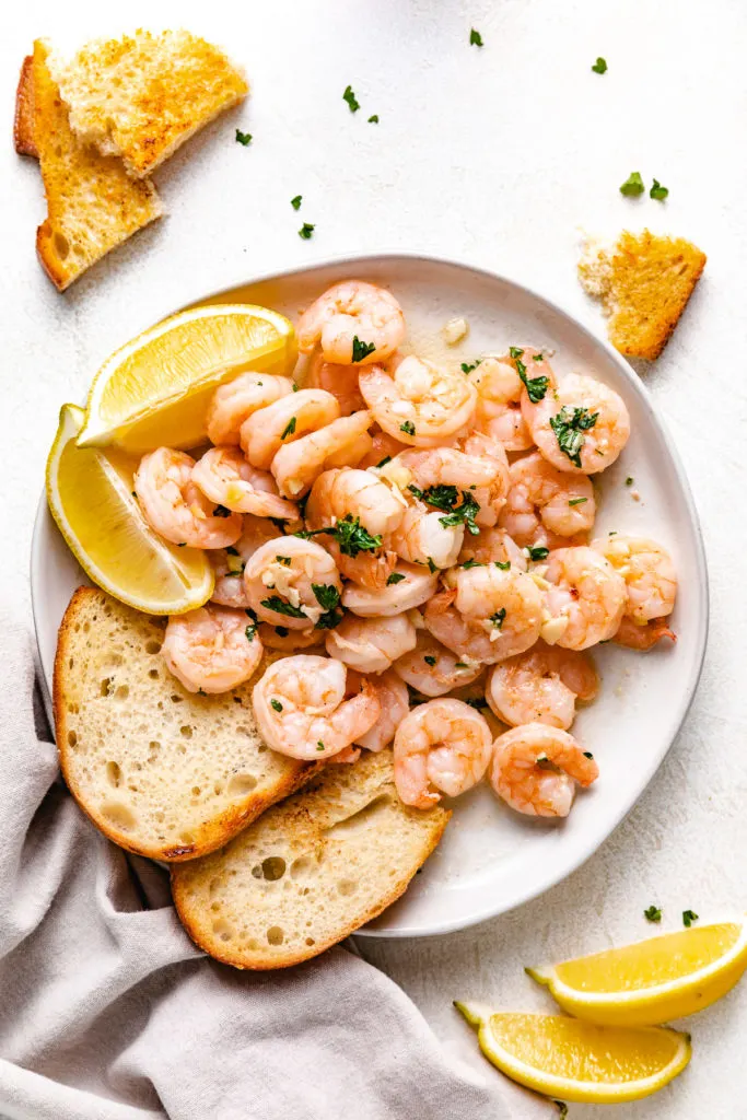 Top down view of shrimp and lemon wedges on a plate.