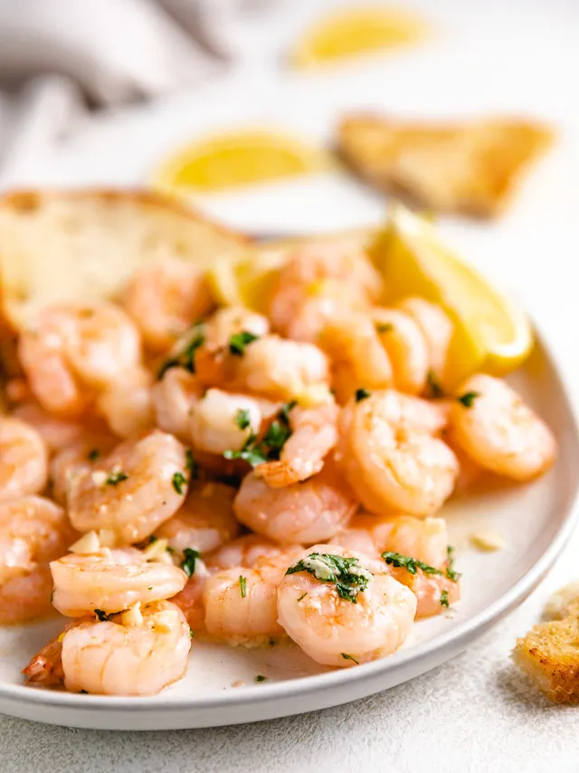 Side view of garlic lemon shrimp on a plate.