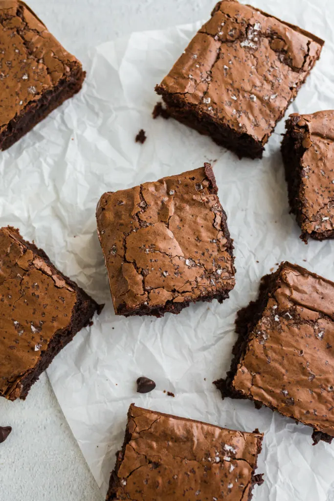 Homemade brownies scattered on parchment.