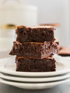 Three brownies in a stack on a plate.