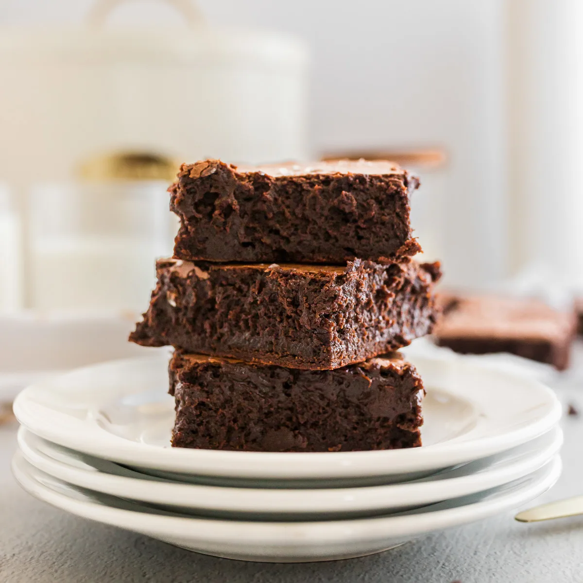 Three brownies in a stack on a plate.