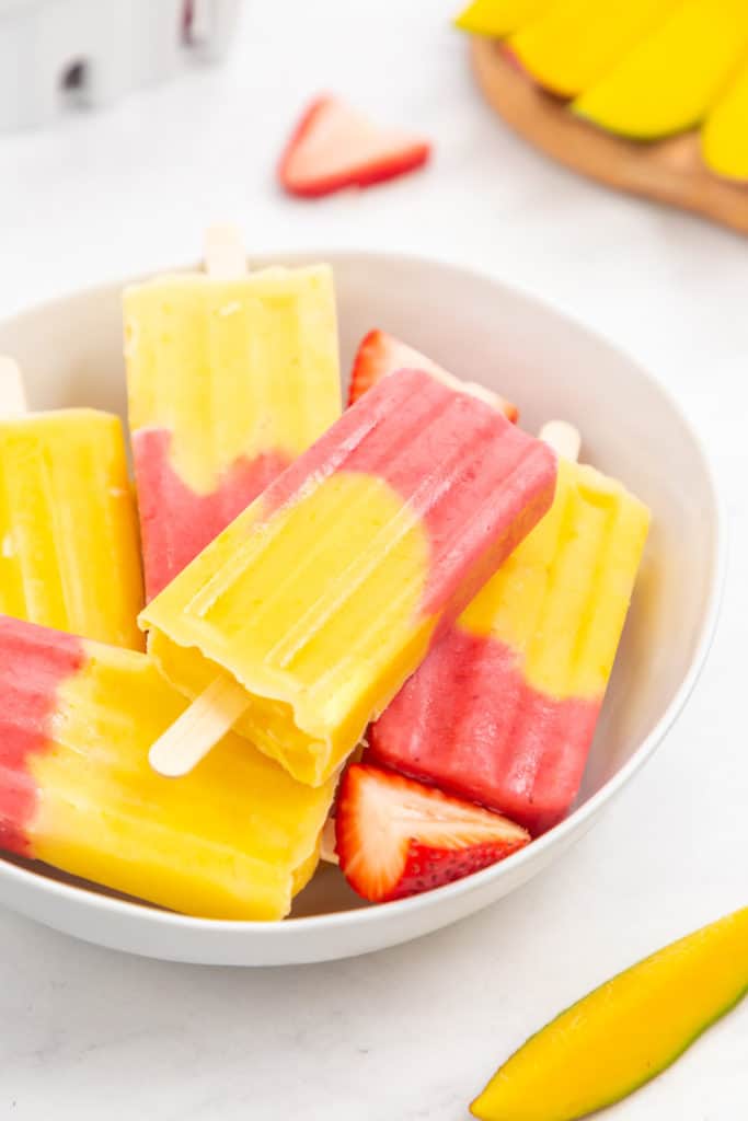 Side view of strawberry fruit popsicles in a bowl.