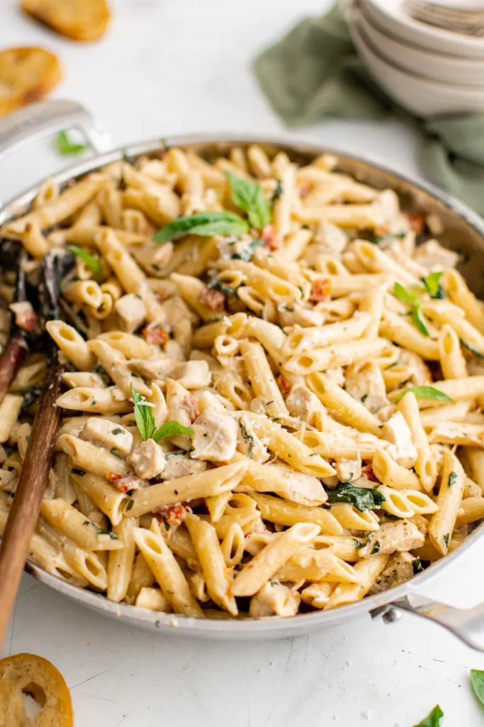 Angled view of chicken tomato spinach pasta in a pan.