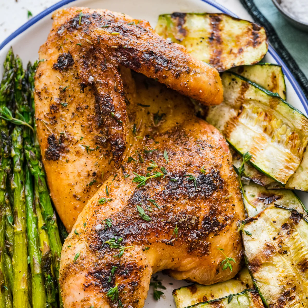 Top down view of grilled half chicken with vegetables.