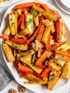 White platter filled with honey roasted carrots and parsnips.
