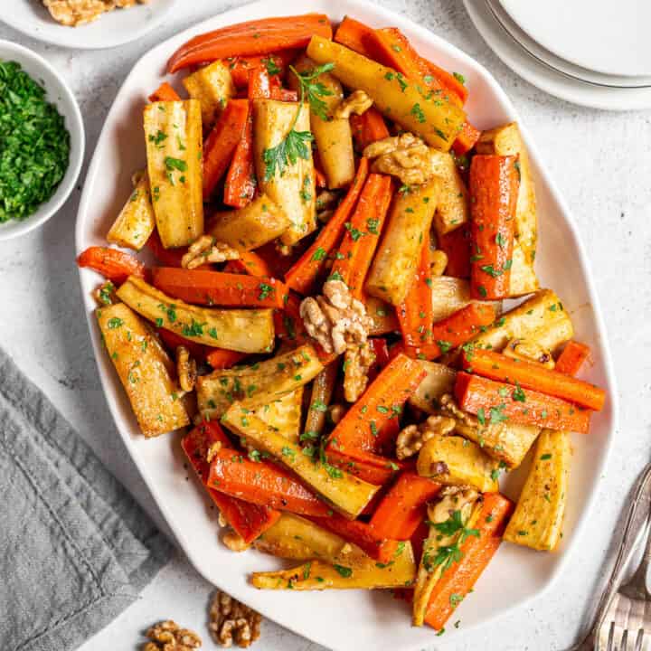 White platter filled with honey roasted carrots and parsnips.
