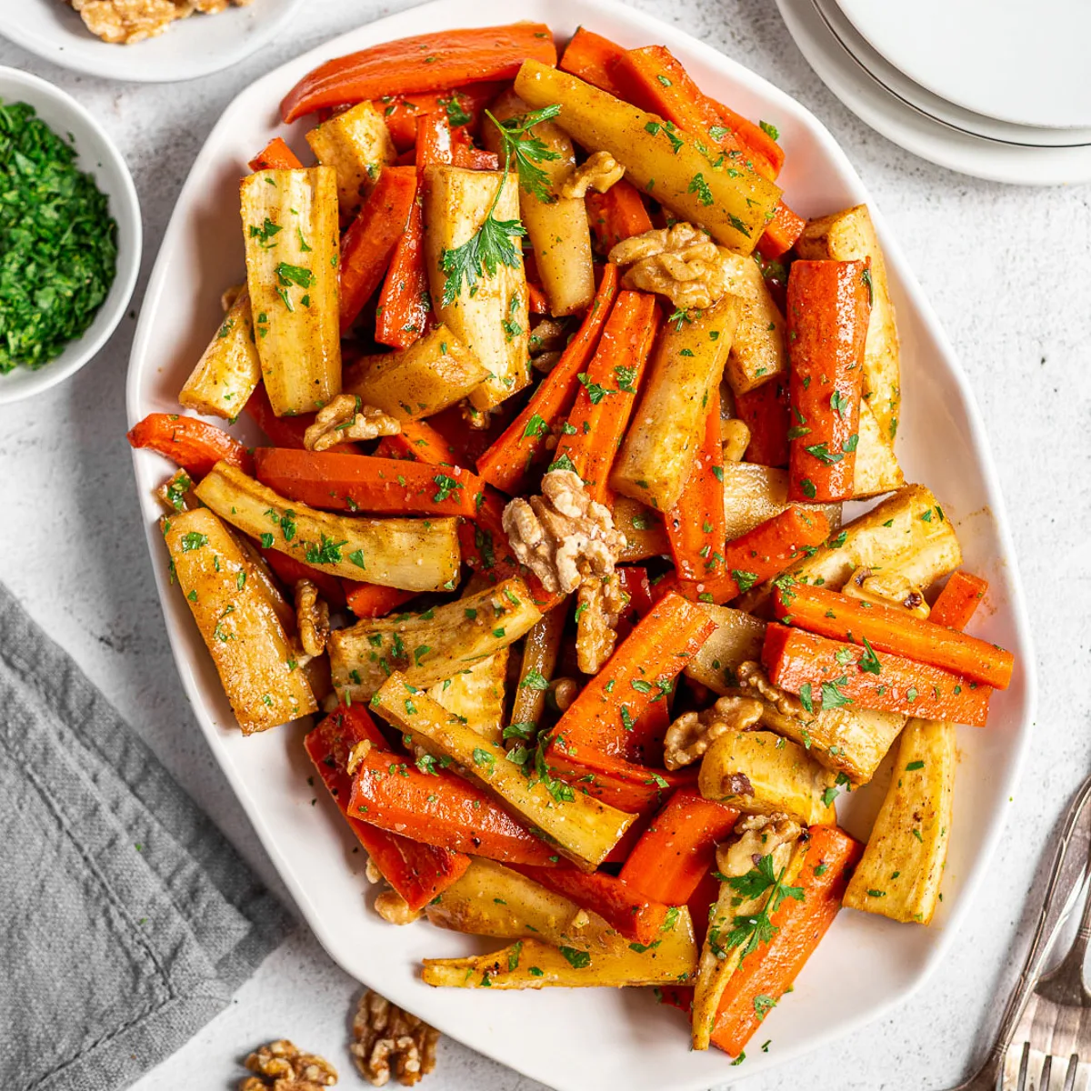 White platter filled with honey roasted carrots and parsnips.